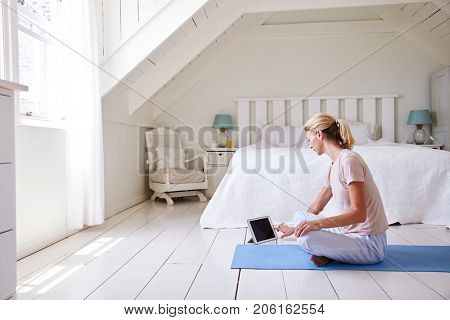 Woman With Digital Tablet Using Meditation App In Bedroom
