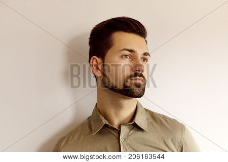 Portrait of serious young man standing against wall.