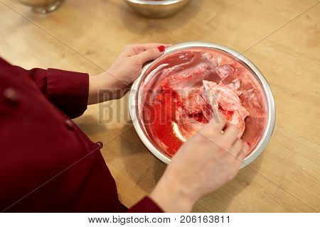 cooking, food and people concept - chef with spatula stirring macaron batter or cream in bowl at pastry shop