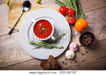 Red ukrainian borsch with sour, garlic, parsley, spices and a lot of dill and parsley on a wooden background. Copy space. Close-up of appetitzing dish. Food concept.