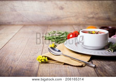 Red ukrainian borsch with sour, garlic, parsley, spices and a lot of dill and parsley on a wooden background. Copy space. Close-up of appetitzing dish. Food concept.