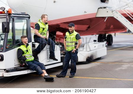 Workers Sitting On Towing Truck While Friend Standing On Runway