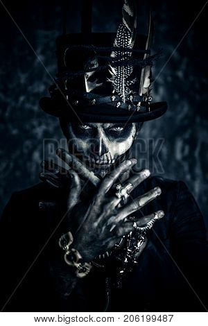 Close-up portrait of a man with a skull makeup dressed in a tail-coat and a top-hat. Baron Saturday. Baron Samedi. Dia de los muertos. Day of The Dead. Halloween.
