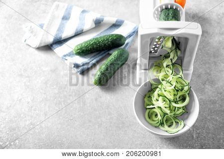Spiral vegetable slicer with cucumber spaghetti on table
