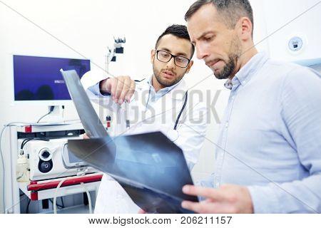 Two men, ragiologist and patient, looking at x-ray images during appointment