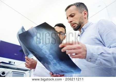 Radiologist explaining patient the problem of his spinal column on x-ray image