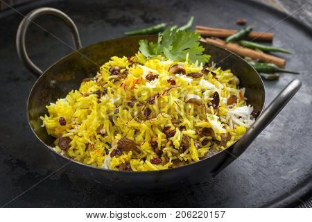 Indian vegetarian biryani with nuts and raisins as close-up in a korai 