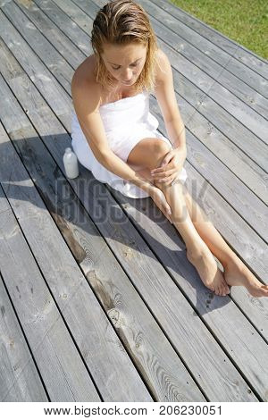 Woman applying body lotion, outdoor bathtime