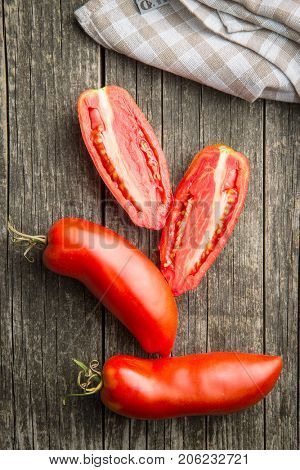 Halved San marzano tomatoes on old wooden table. Top view