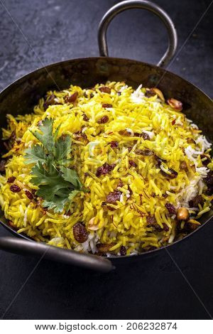 Indian vegetarian biryani with nuts and raisins as close-up in a korai 