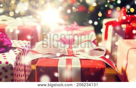 christmas, holidays, presents, new year and celebration concept - close up of gift boxes over christmas tree lights