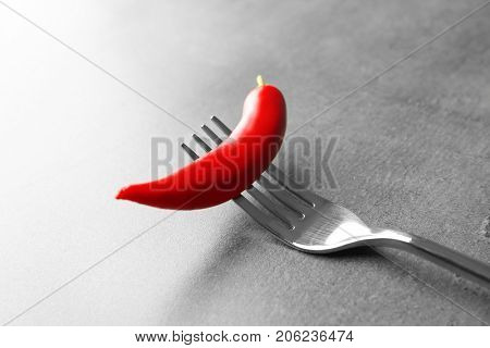 Fork with red chili pepper on gray table
