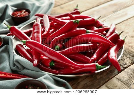 Plate with red chili peppers on wooden table