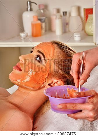 Collagen face mask . Facial skin treatment. Woman receiving cosmetic procedure in beauty salon. Bottle with moisturizing cream on background. Masks for skin tightening.