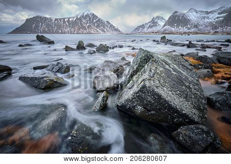 Waves and rocks on coast of Norwegian sea in fjord. Skagsanden beach, Flakstad, Lofoten islands, Norway. Long exposure motion blur