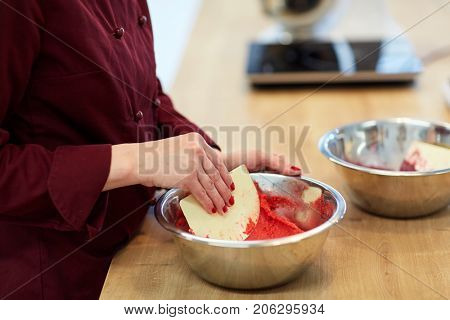 cooking, food and people concept - chef with spatula stirring macaron batter in bowl at pastry shop
