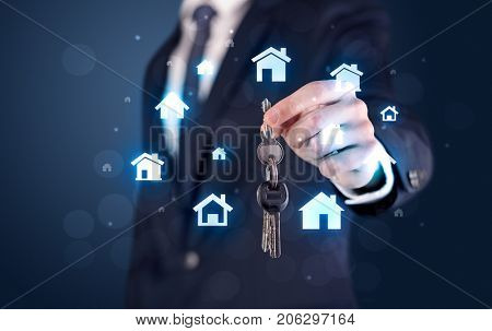 Businessman in suit holding keys with house graphics around and dark background