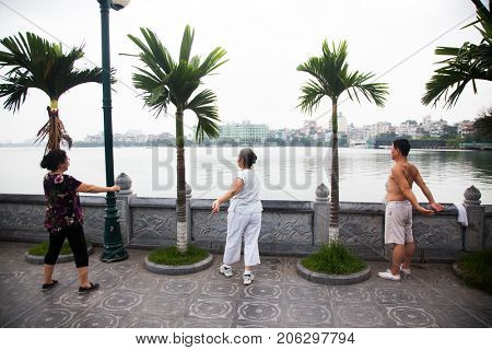 HANOI, VIETNAM - AUGST 2017:  People doing workout in the early morning near Truc Bach lake in Hanoi, Vietnam