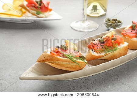 Tasty small sandwiches with salmon and capers on plate
