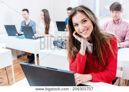 Student woman working on laptop PC in college, group in background