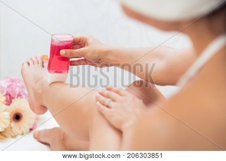 Close-up of the hand of a young woman using a modern recharchable roll-on waxer for removing hair from her legs at home
