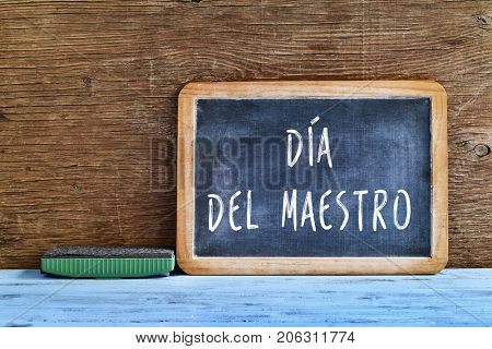 a chalkboard with the text dia del maestro, teachers day written in Spanish, and an eraser on a rustic wooden table, with a retro effect
