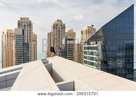 DUBAI, UAE - JAN 13, 2017: Woman on roof near Silverene Tower RMJM (on right), Designed by RMJM, this complex offers 35 floors in Tower A and 26 floors in Tower B