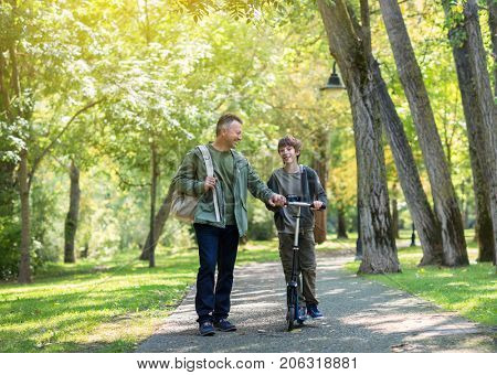 Portrait of father with his son walking together in autumn park. Family leisure. Parenting. Parenthood.