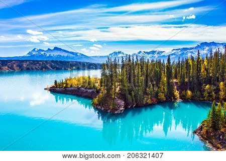 Abraham Lake is in the Rockies of Canada. Turquoise smooth water reflects the sky. Warm sunny day in Indian summer. The concept of ecological and active tourism