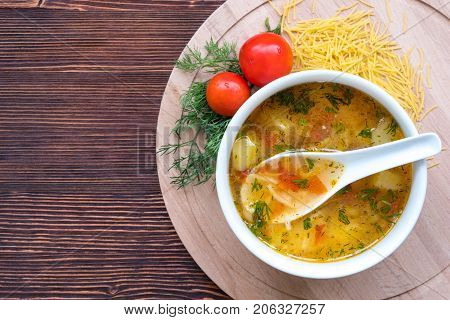 White soup noodles with tomatoes. Potatoes, dill, spices. On a wooden Board.