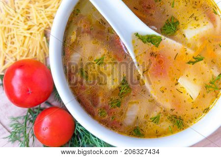 White soup noodles with tomatoes. Potatoes, dill, spices. On a wooden Board.