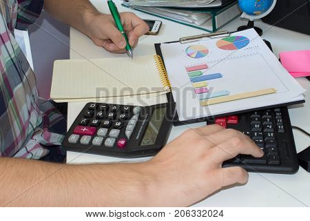 Businessman with computer at the deskdiscussing the charts and graphs showing the results of their successful teamwork. businessman working at a computer hands closeup