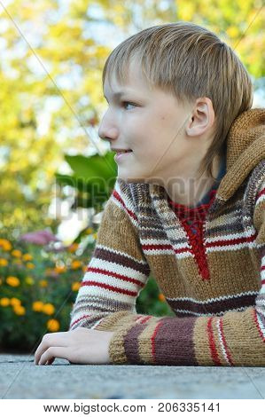 cheerful boy sitting at a table in the garden in autumn
