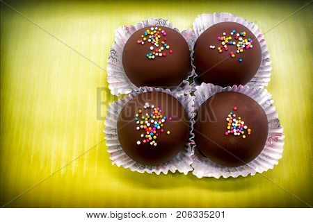 Colorful Chocolate Sprinkles on Tasty Round Chocolate Coated Cakes