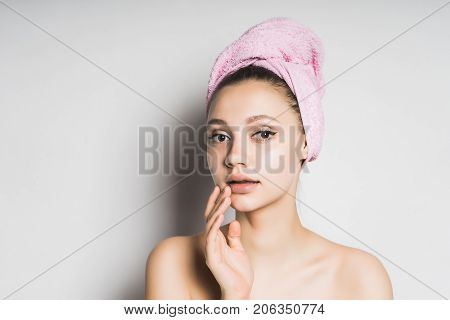 mysterious girl with a pink towel on her head on a white background on spa treatments