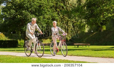 active old age, people and lifestyle concept - happy senior couple riding bicycles at summer park