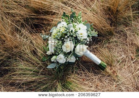 Close-up of wedding bouquet on brown grass.