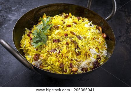 Indian vegetarian biryani with nuts and raisins as close-up in a korai 