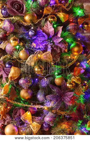 Christmas tree background. Close-up of decorated Christmas tree with golden and purple color decorations.
