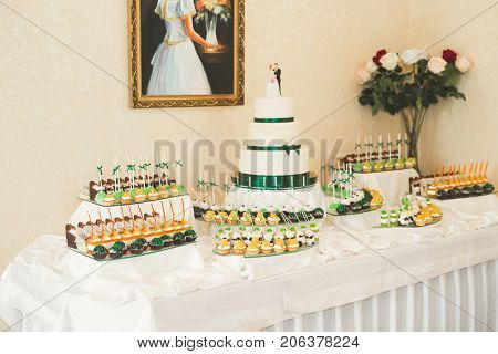 Delicious and tasty dessert table with cupcakes and shots at reception closeup.