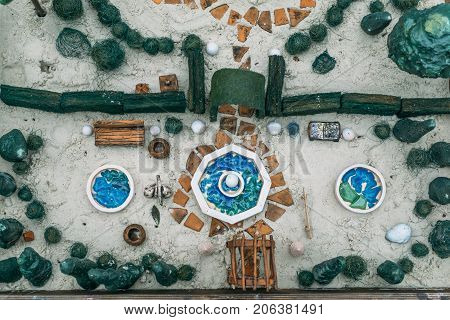 Sand therapy. Top view of toy miniature trees and small elements of landscape in a sand box. Anti-stress psychological rehabilitation therapy
