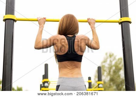 Fit woman exercising outdoors healthy lifestyle and exercise concept. Pullups.