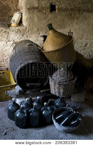 old underground cellar with demijohns and bottles of aged wine