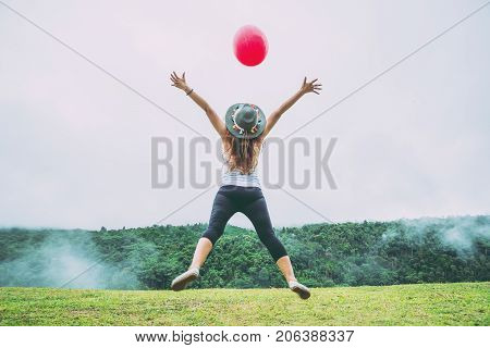 Asian women travel relax in the holiday. Stand Jump on a natural grassy mountain