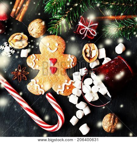Christmas composition with Christmas gift gingerbread man cookie fir tree branches xmas holiday decorations and festive symbols on black background with copy space for your design or Merry Christmas text