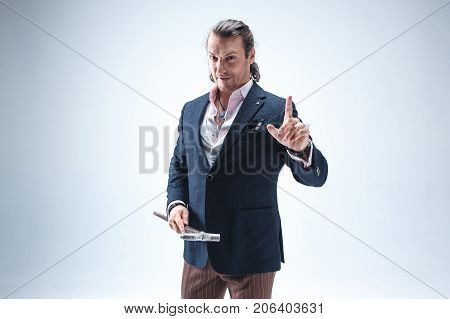 The mature bearded man in a suit holding cane. Isolated on a blue studio background.