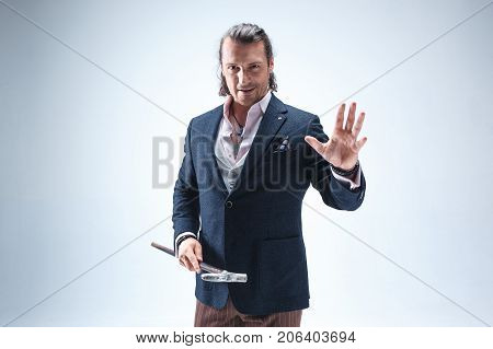 The mature bearded man in a suit holding cane. Isolated on a blue studio background.