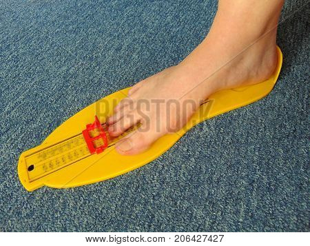 yellow foot measurement device with naked foot upon with measuring tape