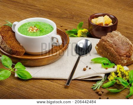 Green vegetable cream soup with celery and broccoli. Black bread with garlic and onions. Crackers of white bread. Many fresh and healthy vegetables. Close-up of cream soup. Copy space. Food concept.