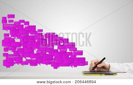 Hand of man using tablet and chatboxes flying out